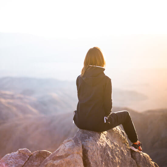Woman sitting on the summit of a mountain