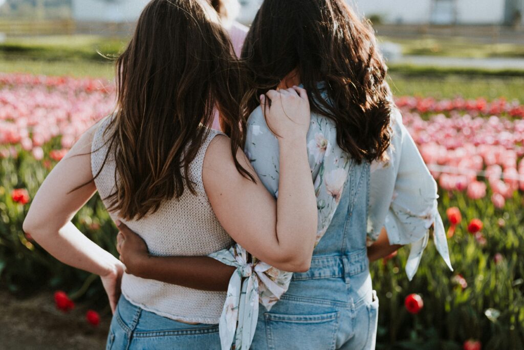 two empowered women hugging each other in front of a flower field